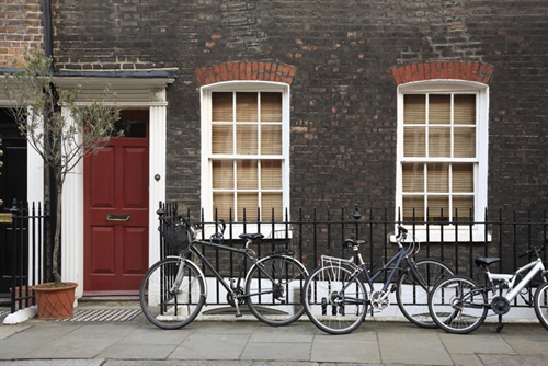 Bicycles against a railing outside a house.