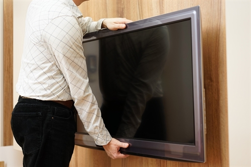 A man taking a flatscreen TV.