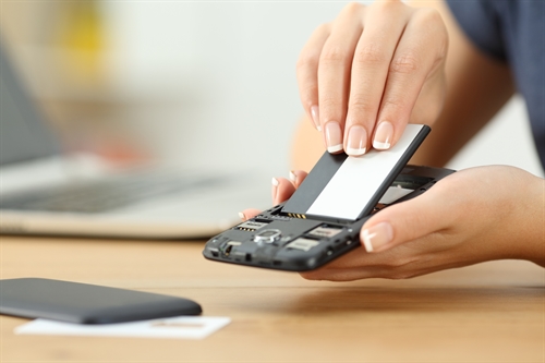 Woman removes battery from a smartphone before putting it in storage