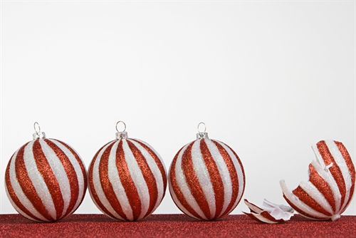 Decorative: A row of striped Christmas baubles, one of which is broken -- to suggest a stressful festive situation.