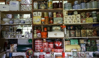 a collection of tins and vintage storage kept on cluttered shelves with a window behind.